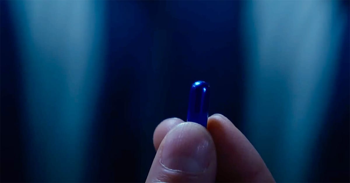 A close-up of a hand holding the blue pill in a scene from "The Matrix."