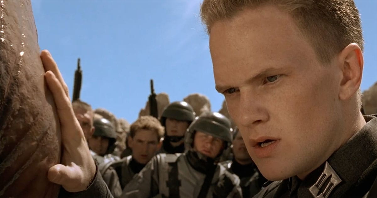 Carl Jenkins examines the Brain Bug with Mobile Infantry soldiers watching in "Starship Troopers."