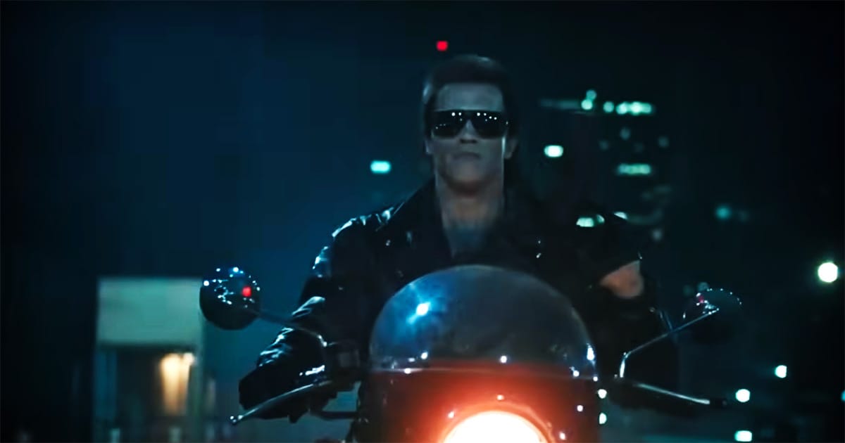 "The Terminator, clad in leather and sunglasses, rides a motorcycle through the city streets at night."