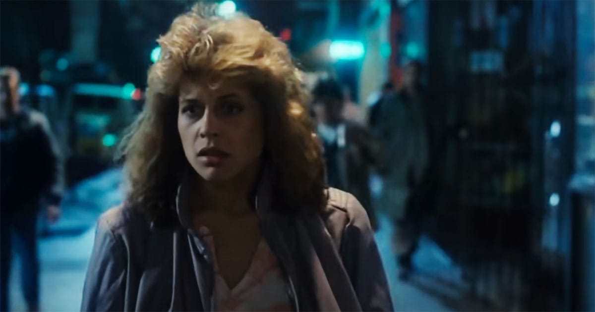 "Sarah Connor walking through a dark city street, unaware of the looming threat that will change her life forever."