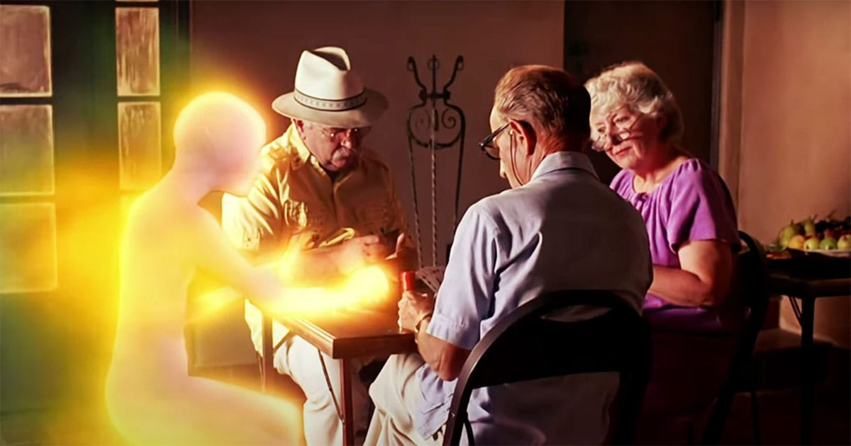 Glowing alien figure playing cards with elderly humans.