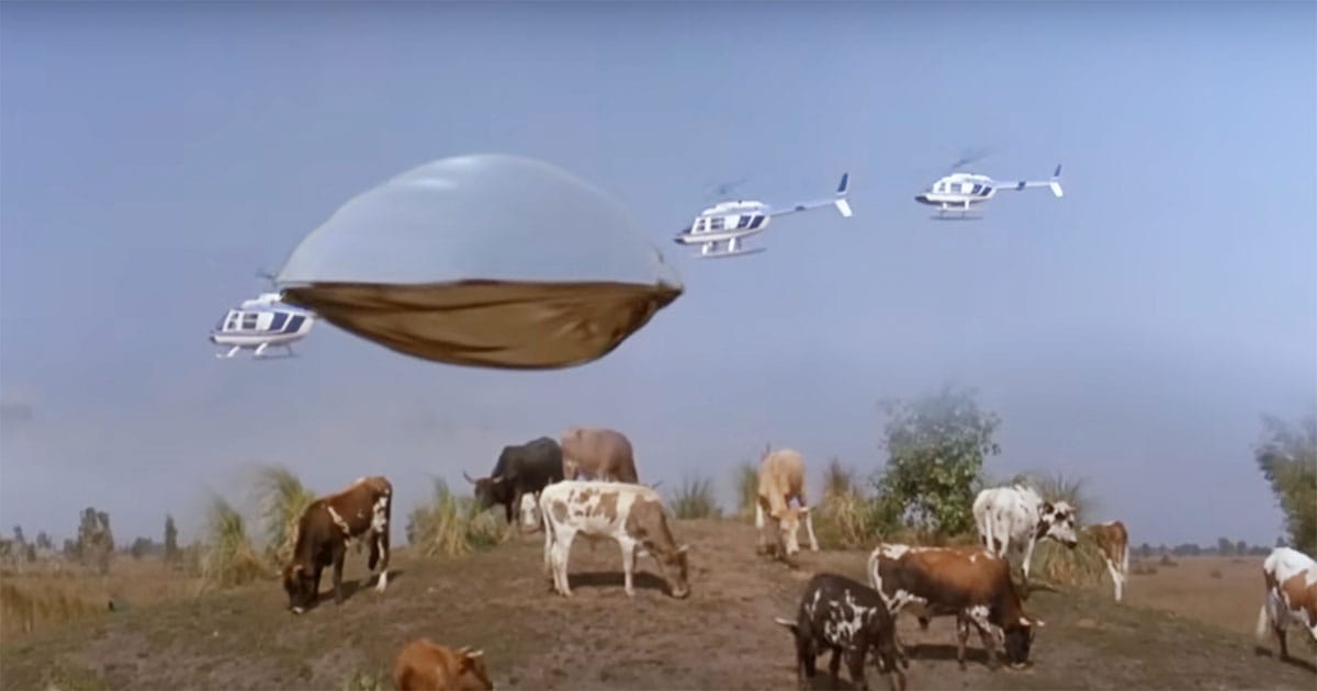 The spaceship from Flight of the Navigator is chased by helicopters over a field of cattle.
