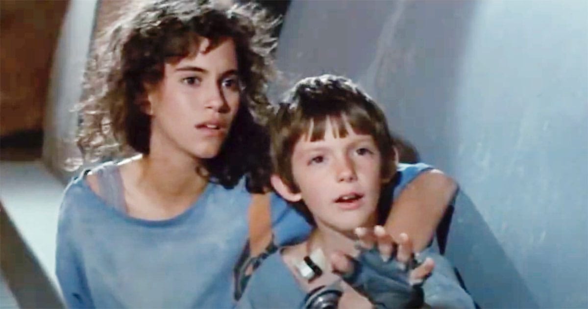 Close-up of Daniel and Terra in Solarbabies looking ahead with awe and hope in a dim corridor.