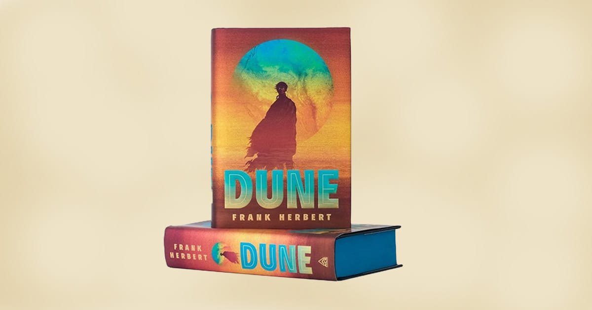 Hardcover edition of Frank Herbert's Dune with colorful cover art showing a cloaked figure in front of a glowing planet.