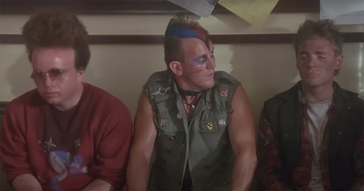 Three gang members from "The Wraith" sitting tensely in a police station, reflecting the film’s themes of revenge and reckoning.