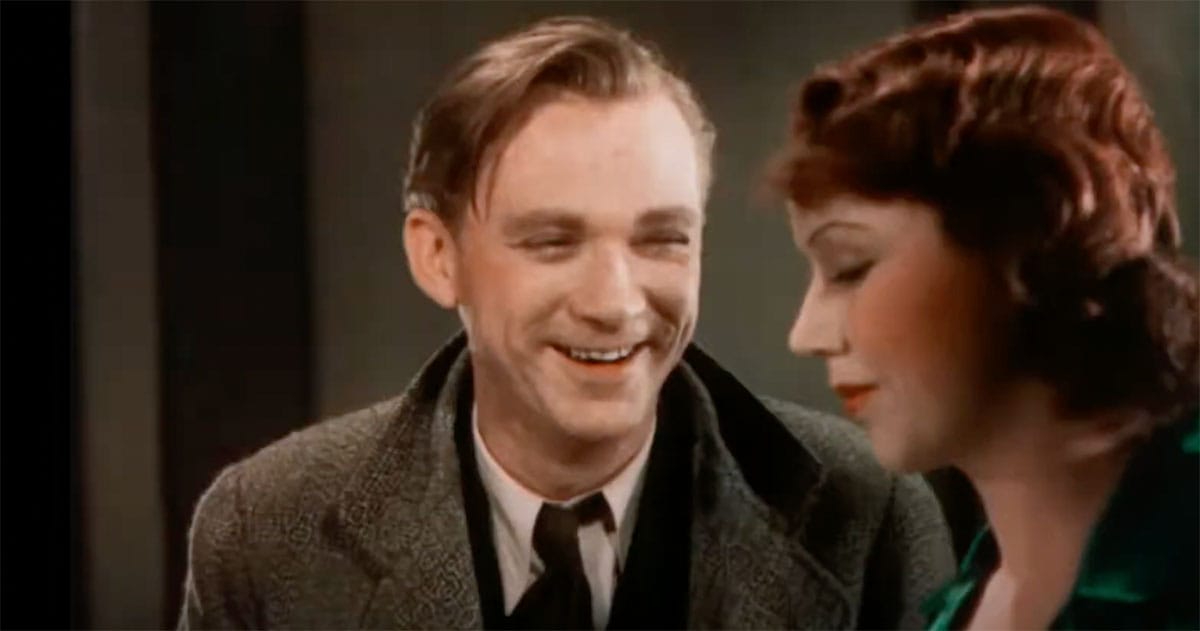 Scene from the 1932 film "Doctor X" showing a man smiling and a woman in green dress in restored two-strip Technicolor.