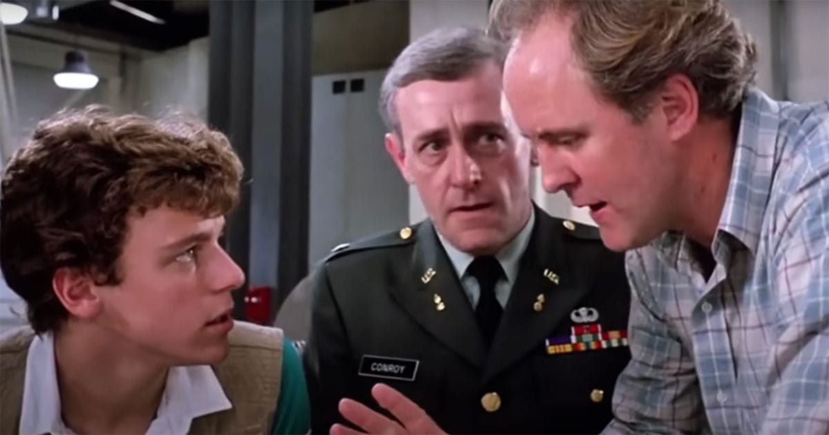Paul Stephens faces questioning from a military officer and a scientist inside a government lab in "The Manhattan Project" (1986).