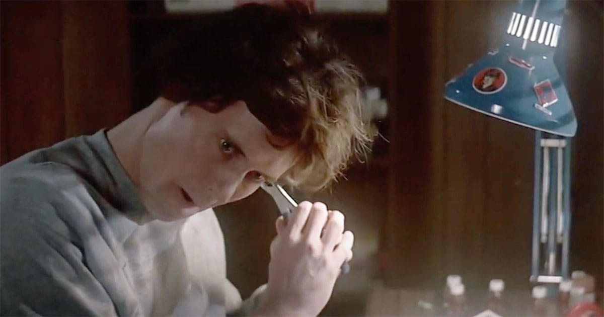 The Beta Unit version of Alex carefully adjusting his artificial ear with a tool at a desk.