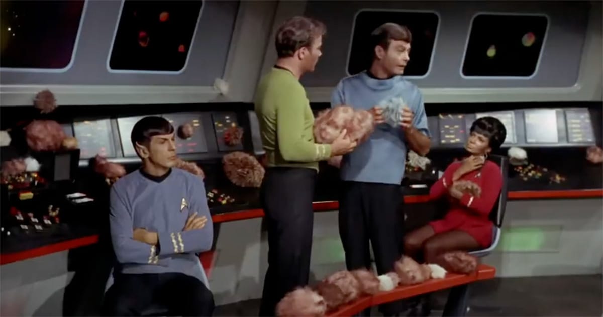 Captain Kirk, Mr. Spock, Dr. McCoy, and Lieutenant Uhura surrounded by tribbles on the Enterprise bridge in “The Trouble with Tribbles.”