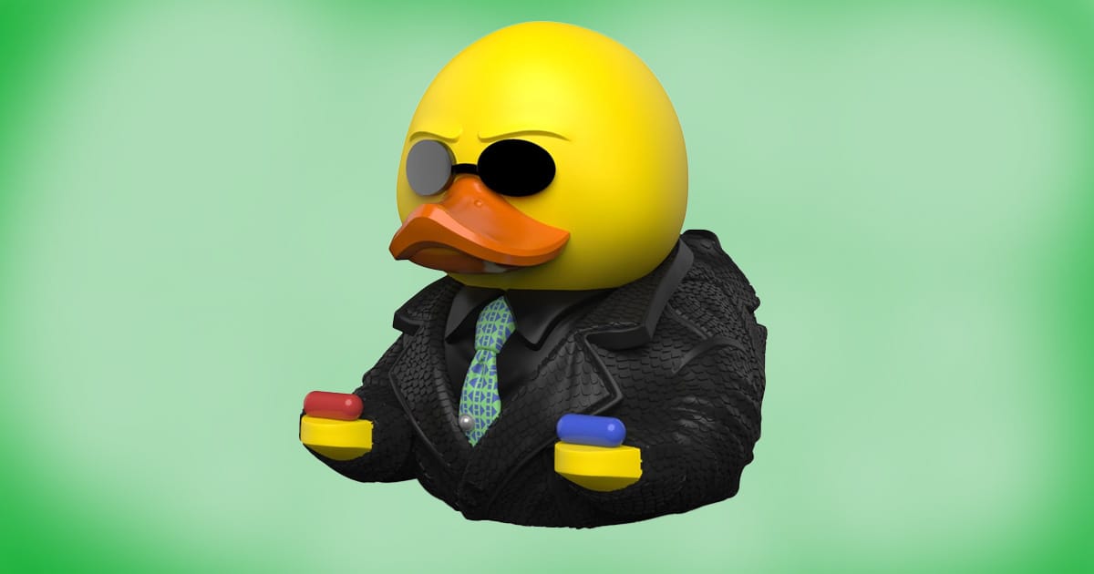 Morpheus rubber duck collectible from The Matrix holding red and blue pills, wearing black coat and sunglasses, parody figure by TUBBZ.