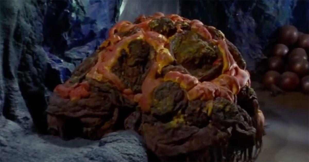 The Horta alien from "Star Trek: The Original Series" with molten rock-like body and glowing patterns inside cave setting.