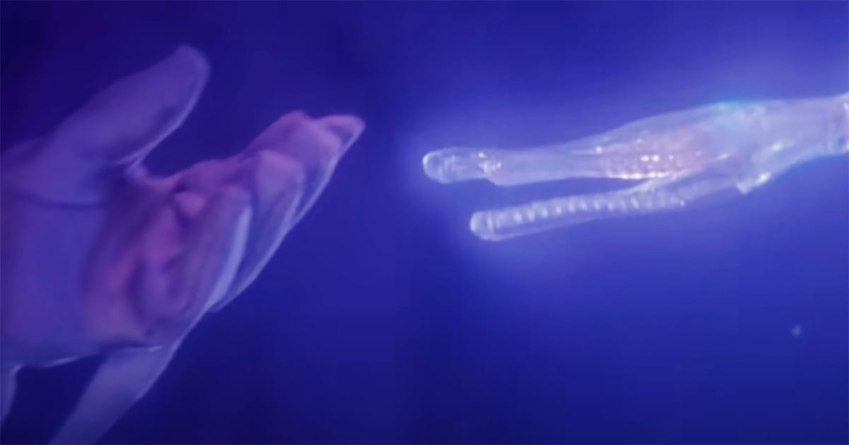 Human hand reaching toward glowing alien hand underwater in The Abyss representing contact and compassion.
