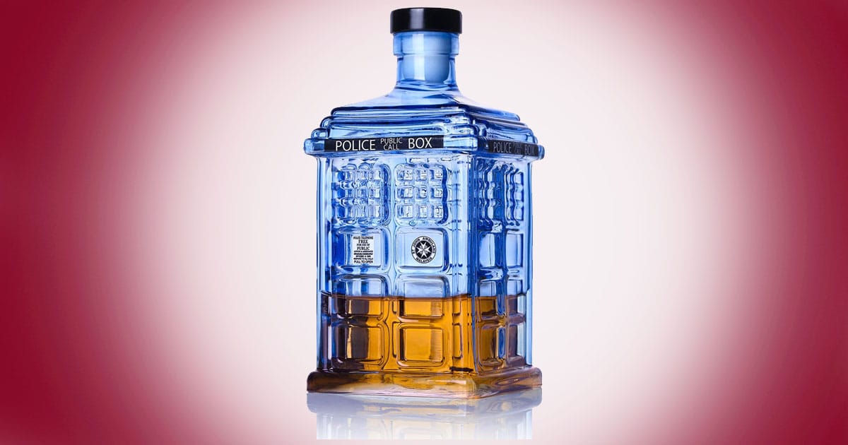 Doctor Who TARDIS blue glass whiskey decanter partially filled with amber liquid on red background.