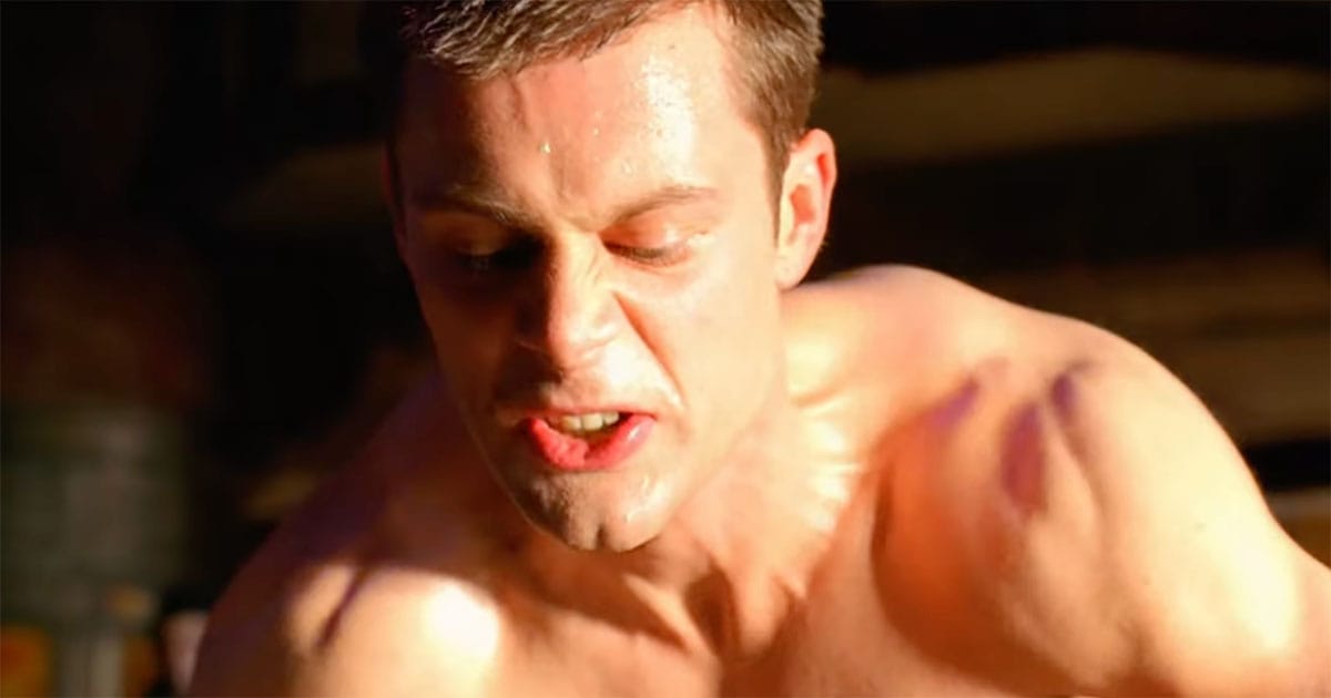 Actor Matt Keeslar as Feyd-Rautha, face tense and sweating, caught mid-combat under bright golden light.