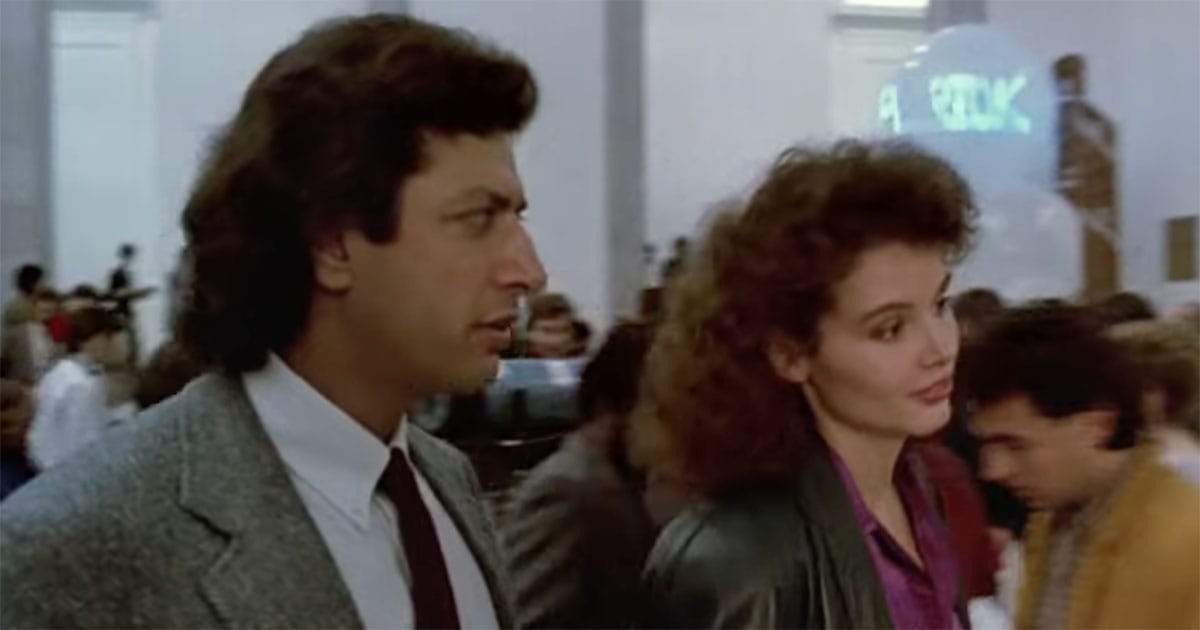 A scientist and a journalist walk together through a crowded event early in their story.