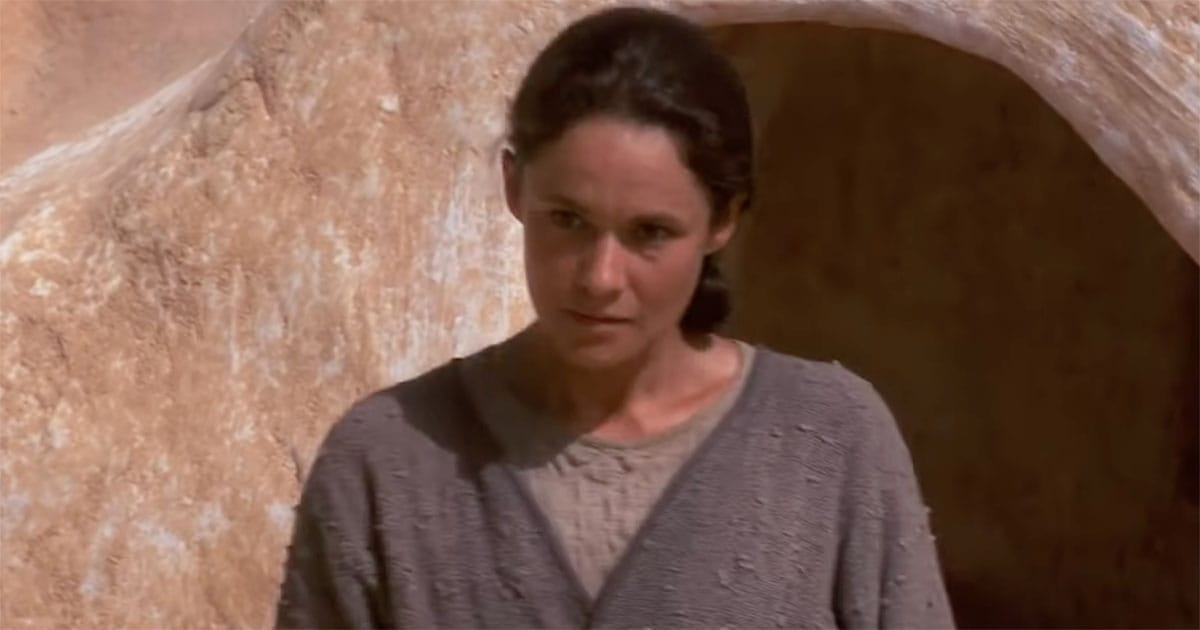 Shmi Skywalker standing outside her home on Tatooine with a solemn, reflective expression.