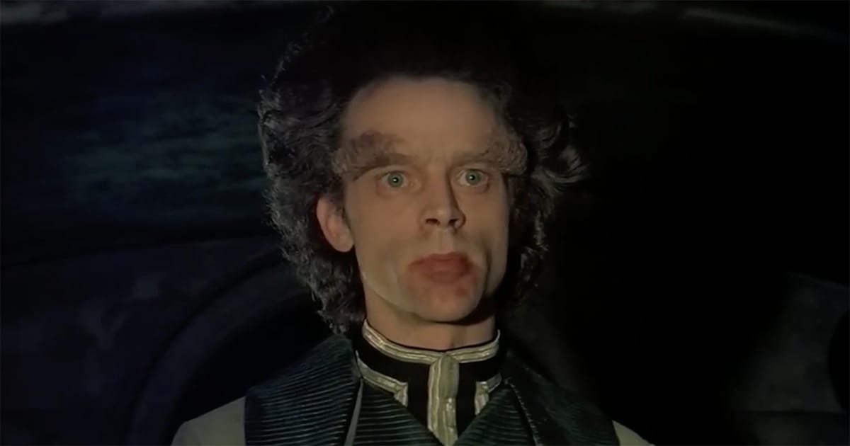 Brad Dourif as Piter de Vries, expression fixed between revelation and ruin, lit by harsh Harkonnen light.