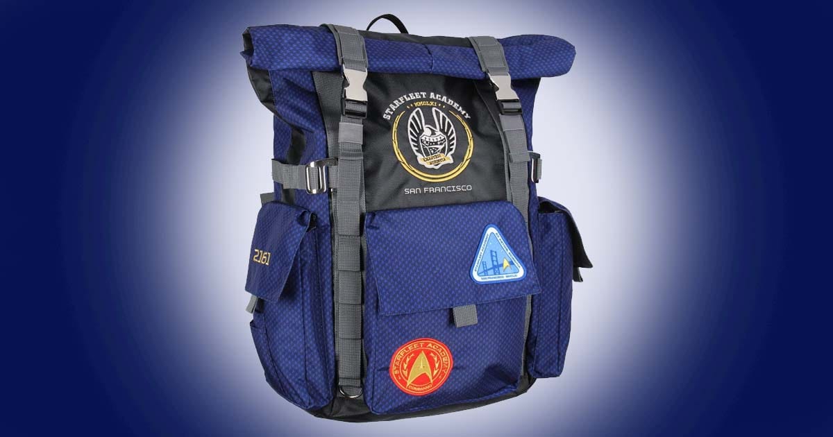 Star Trek Starfleet Academy roll top backpack in blue with embroidered insignia and multiple compartments shown against a dark blue background.
