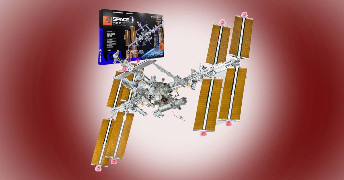 Solar powered International Space Station building kit with extended solar arrays, shown assembled alongside its product box.
