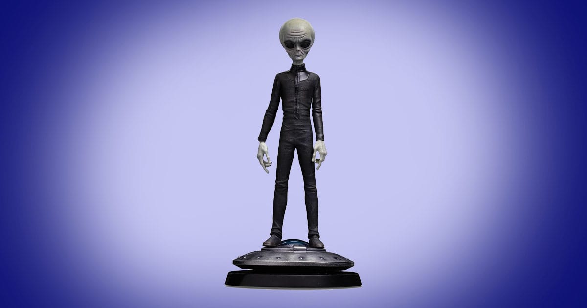 Grey alien statue standing on UFO style base with large black eyes and slender body science fiction collectible.