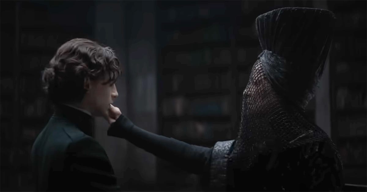 Reverend Mother Gaius Helen Mohiam in Dune 2021 touching Paul Atreides’ chin during the Gom Jabbar test, veiled and imposing in a dark chamber.
