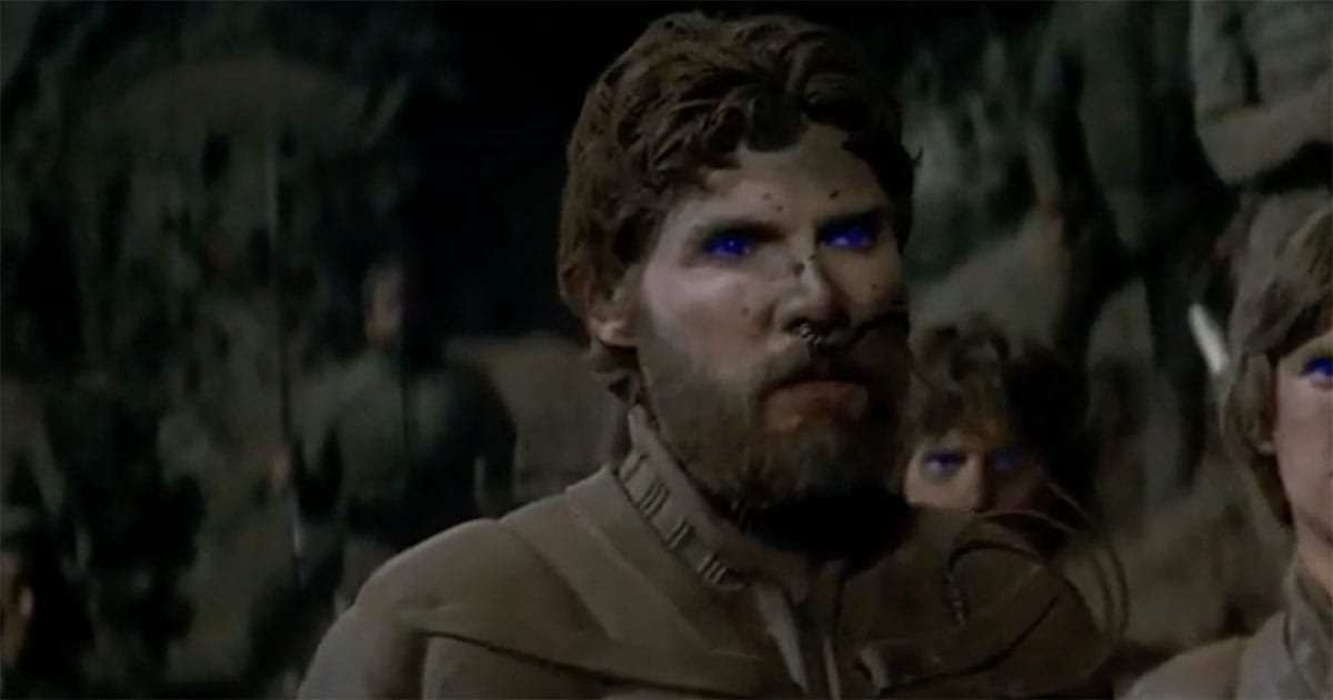 Stilgar standing among the Fremen inside a cave on Arrakis, his blue eyes showing prolonged exposure to spice.