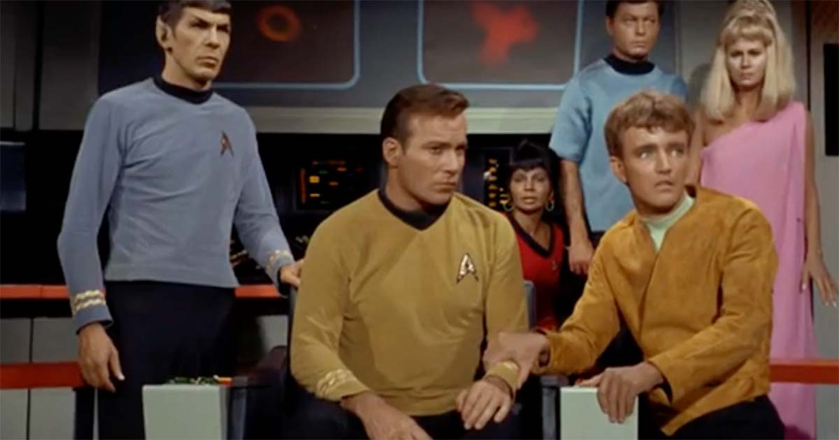 The crew gathered on the Starship Enterprise bridge with the captain seated, showing the chair as an accepted part of the setting.