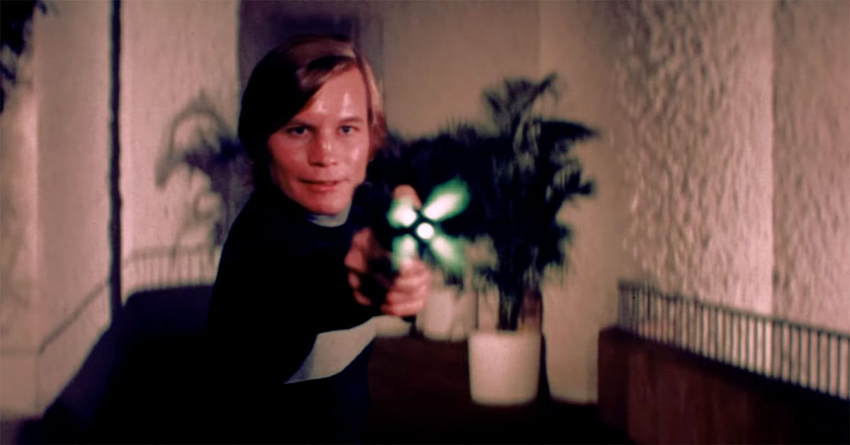 Logan aiming his weapon inside the domed city in the 1976 science fiction film Logan’s Run.