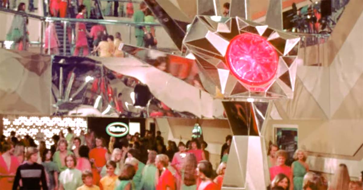 Crowds of citizens walking through the interior concourse of the domed city in the 1976 science fiction film Logan’s Run.