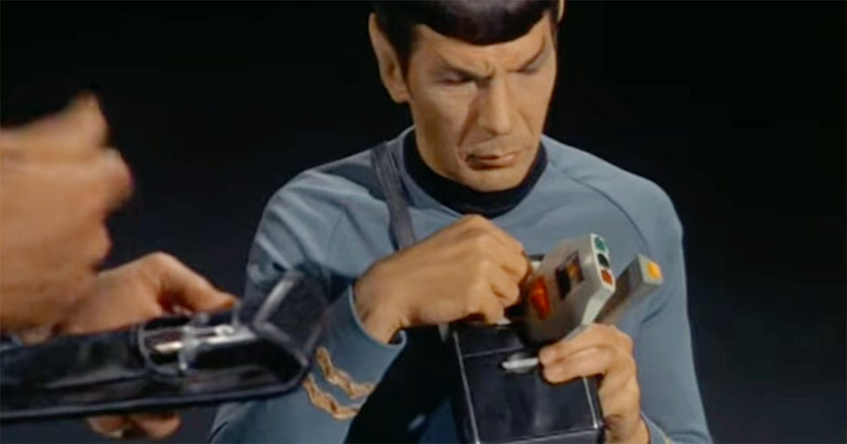 Spock operating an open tricorder with a handheld probe during Star Trek The Original Series, showing illuminated controls and mid-use handling.