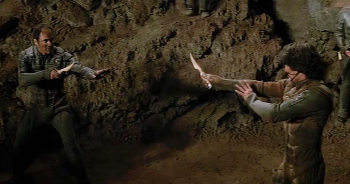 Paul Atreides and Jamis facing each other with crysknives inside a Fremen cavern in the 1984 Dune film.