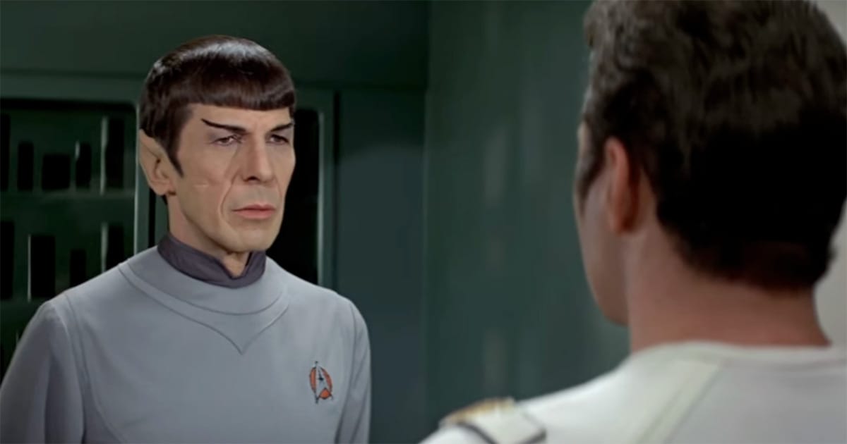 Leonard Nimoy as Spock in gray Starfleet uniform facing Captain Kirk in Star Trek scene.