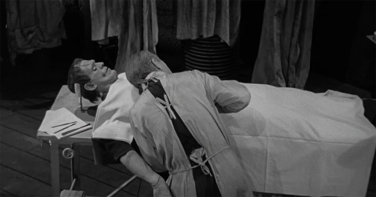 Laboratory scene from the 1931 film Frankenstein showing a figure lying on a table while another leans close, emphasizing aftermath rather than action.