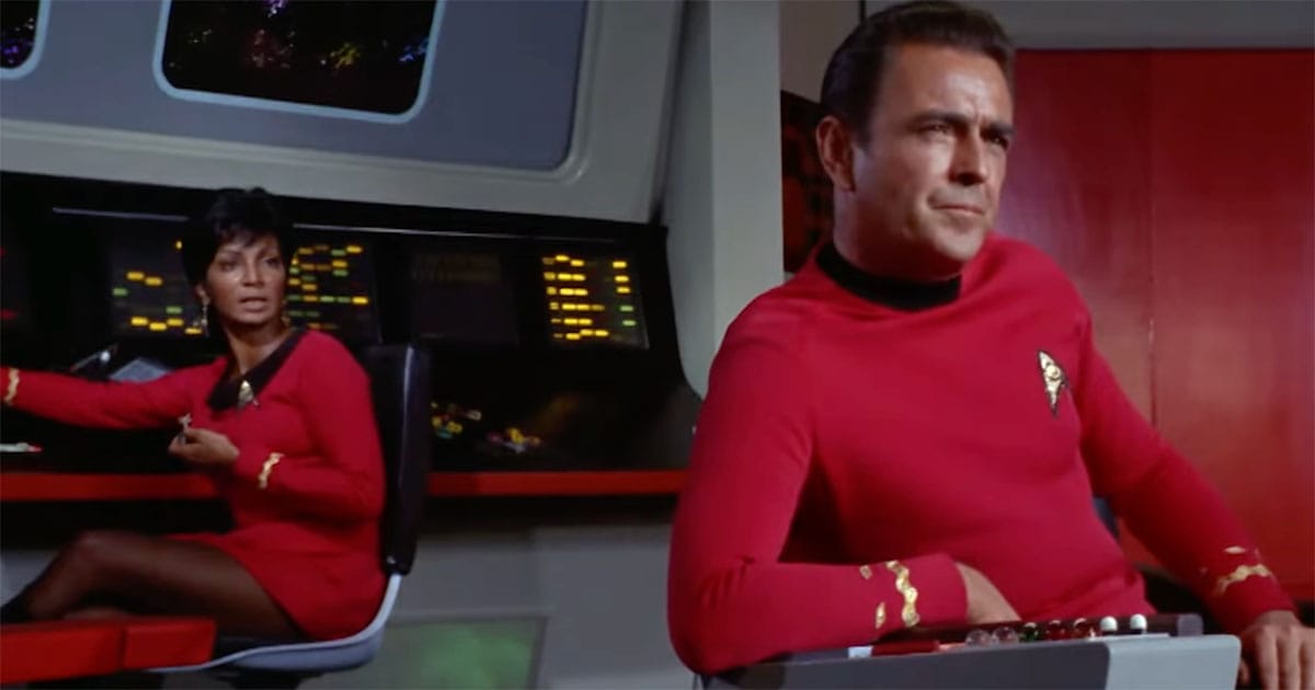 James Doohan as Scotty seated in the captain’s chair with Lieutenant Uhura on the bridge of the original Star Trek series.
