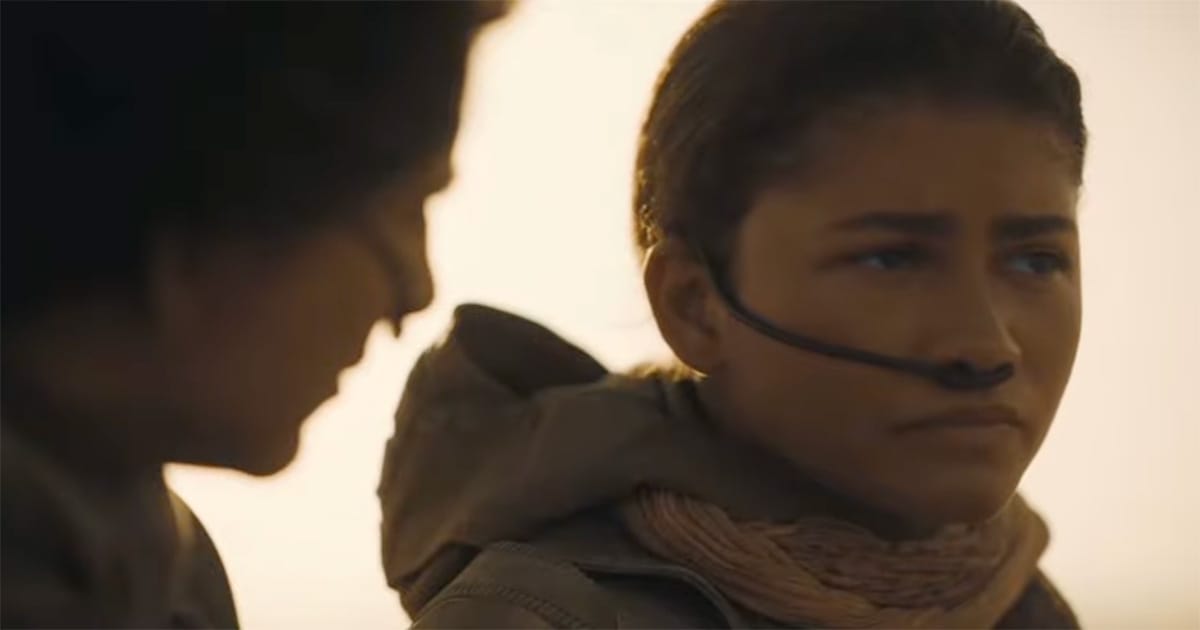 Chani and Paul Atreides walking in the desert wearing stillsuits in a scene from "Dune" 2021.