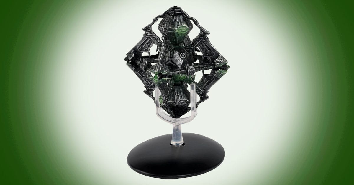Model of the Borg Queen Ship from Star Trek featuring dark geometric structure with green illuminated details mounted on a display stand.