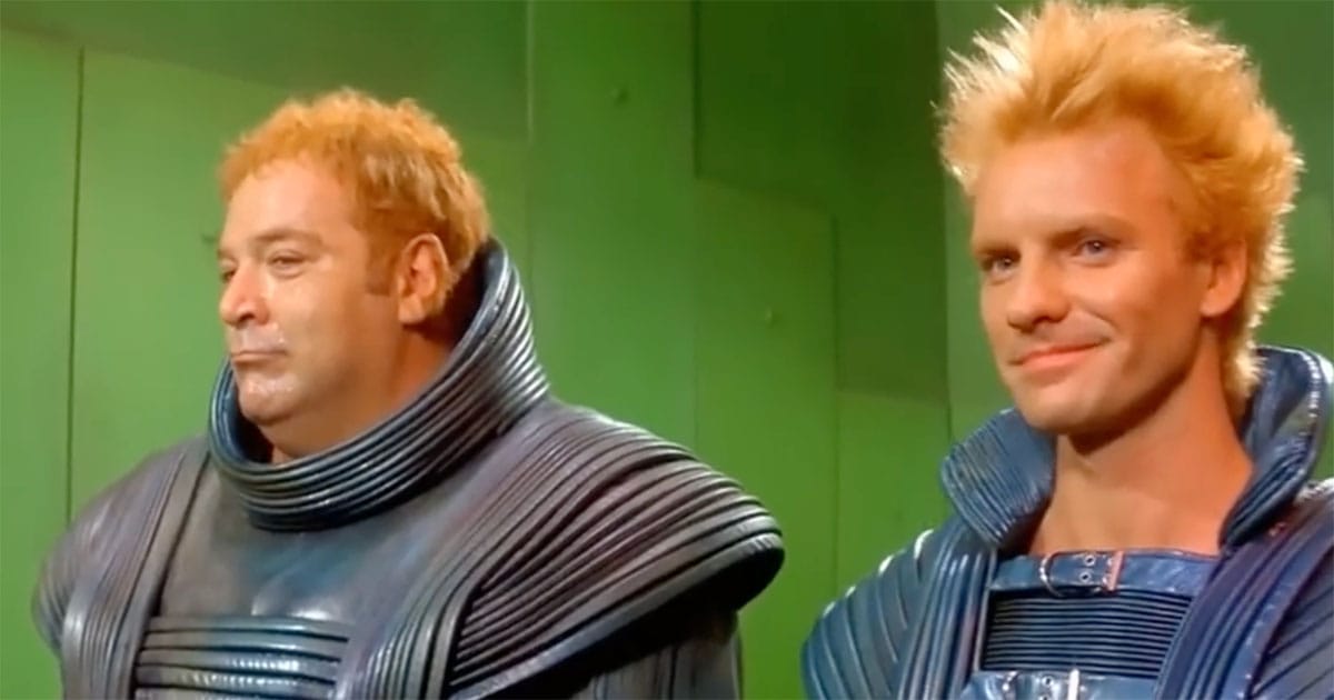 Paul L. Smith as Glossu Rabban and Sting as Feyd-Rautha standing together in blue armor beneath green Harkonnen light