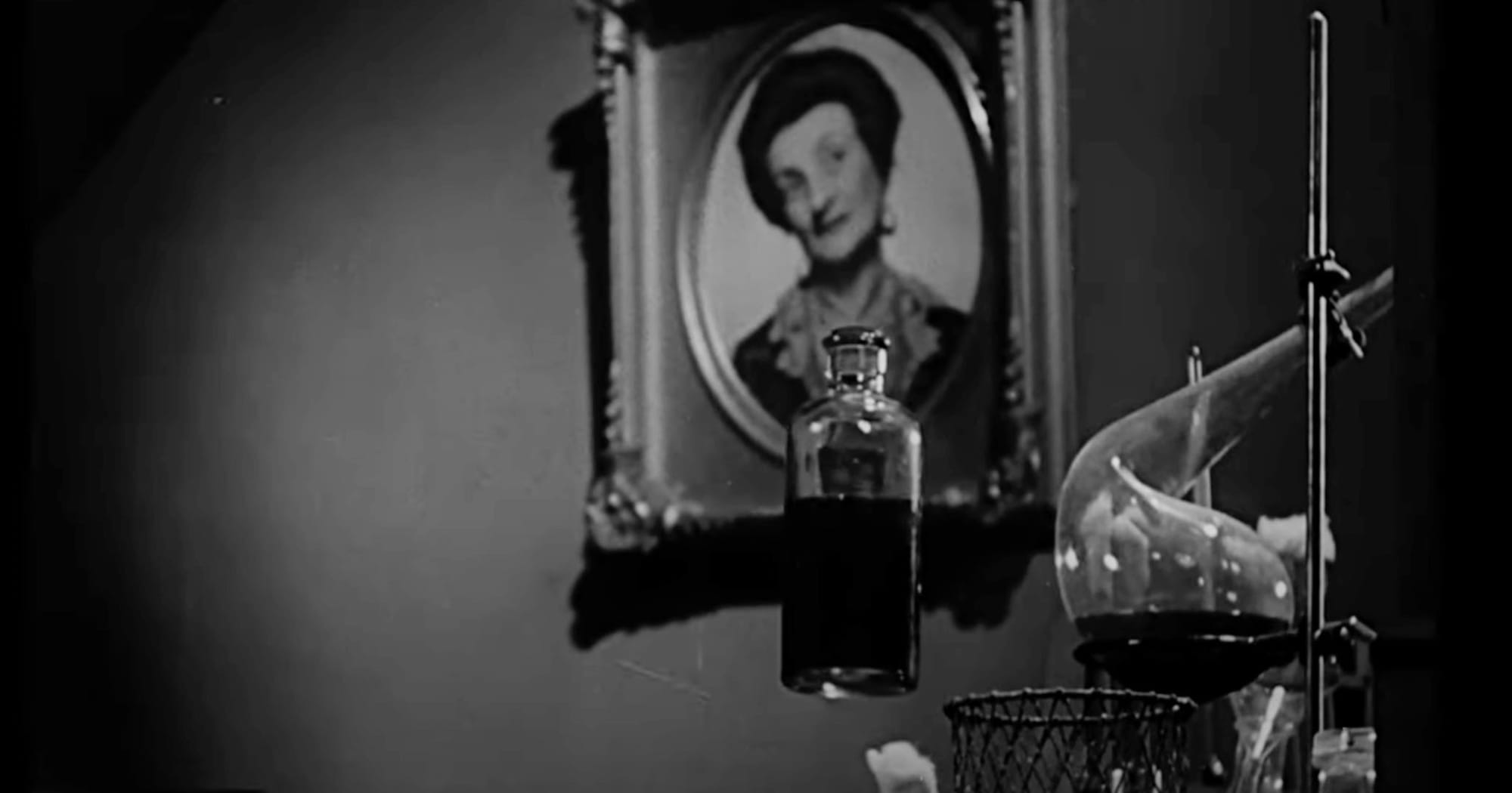 Laboratory glassware and a floating bottle symbolize the power and peril of unseen discovery in The Invisible Man (1933).