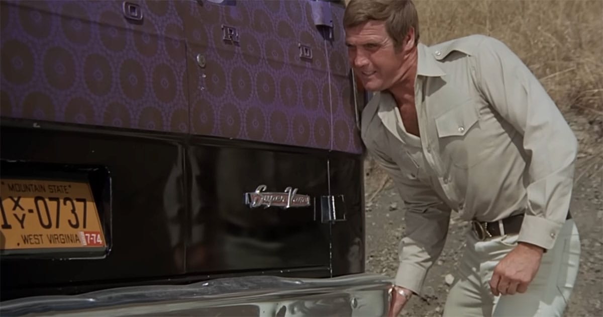 Steve Austin uses bionic strength to lift a vehicle in a scene from The Six Million Dollar Man