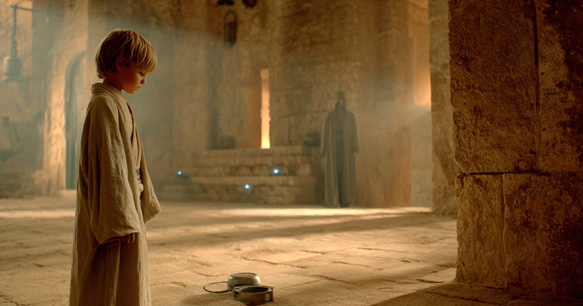 Young child in robes standing in temple with small device on the ground representing Jedi evaluation and midi-chlorian testing in Star Wars.