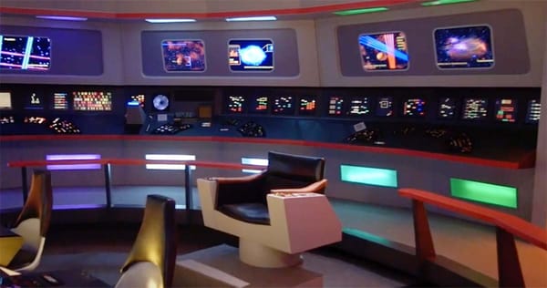 Wide view of the original "Star Trek" Enterprise bridge with captain’s chair and consoles featuring colorful jelly bean buttons and futuristic displays.