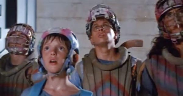 Teenage characters in futuristic gear looking upward in awe beneath the Eco Protectorate emblem in Solarbabies