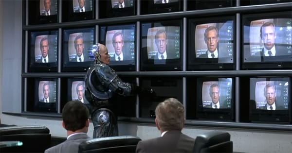 RoboCop stands before a wall of television screens showing an OCP executive, symbolizing corporate control over law enforcement in the 1987 science fiction film.
