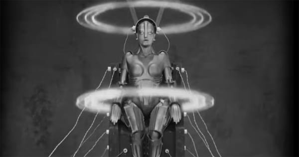The robot Maria from Metropolis (1927) during her transformation sequence, seated with glowing energy rings circling her body in a dramatic laboratory scene.
