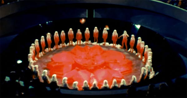 Carrousel ceremony with citizens standing in a circle around the red renewal flower in the 1976 science fiction film Logan’s Run.