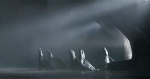 Several cloaked Bene Gesserit sisters process across a dark, misty chamber beneath angled white light.