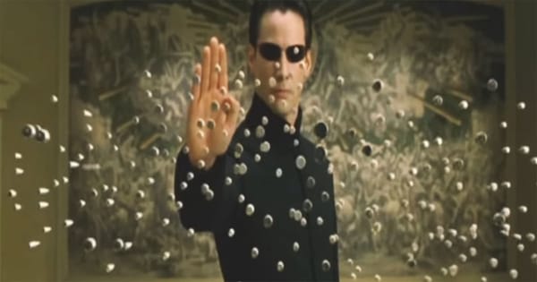 Neo halting bullets inside the simulated world in The Matrix, symbolizing perception, control, and awareness of an artificial reality.